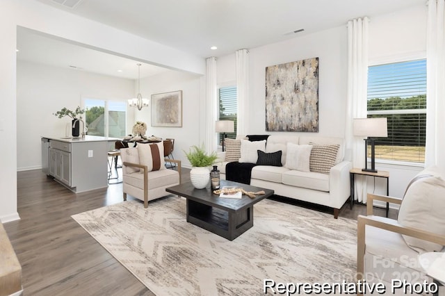 living area featuring a chandelier, recessed lighting, baseboards, and wood finished floors