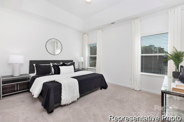 bedroom featuring light carpet, visible vents, baseboards, and a raised ceiling