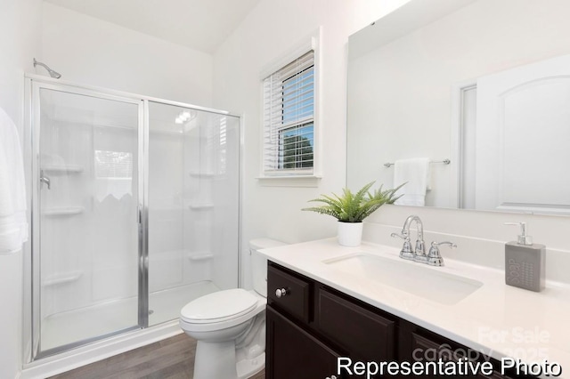 full bathroom featuring wood finished floors, a stall shower, vanity, and toilet