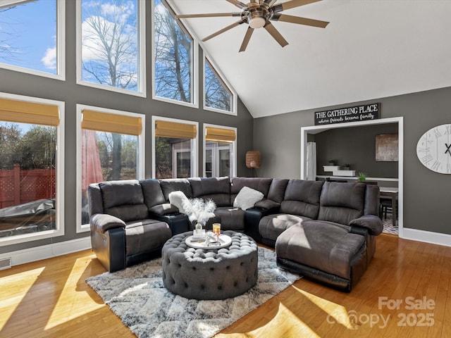 living room featuring visible vents, light wood-style floors, ceiling fan, high vaulted ceiling, and baseboards