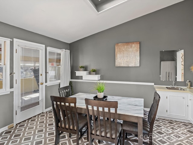 dining room with light floors, lofted ceiling, and baseboards