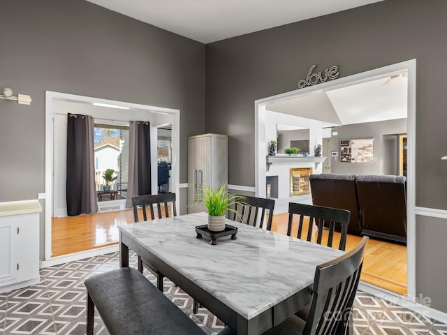 dining space with light wood finished floors and a glass covered fireplace