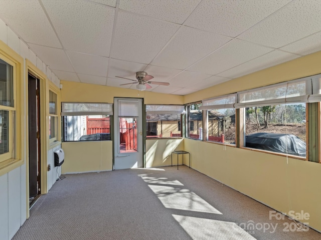 unfurnished sunroom featuring a ceiling fan and a drop ceiling