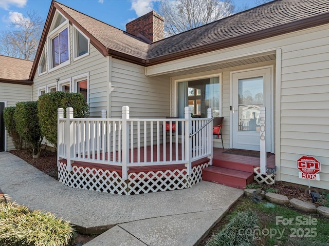 exterior space with a shingled roof, a porch, and a chimney