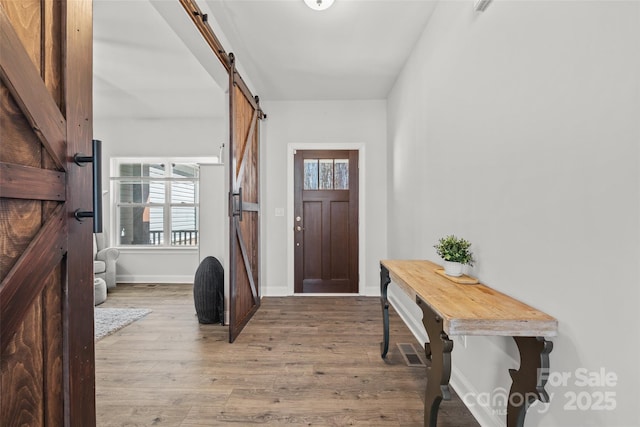 entryway featuring light wood-style floors, baseboards, and a barn door