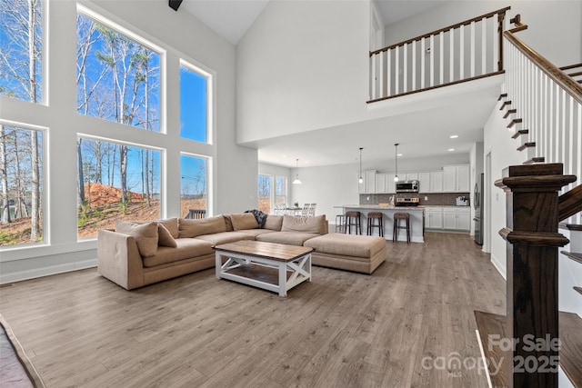 living room with light wood-style floors, baseboards, stairway, and recessed lighting