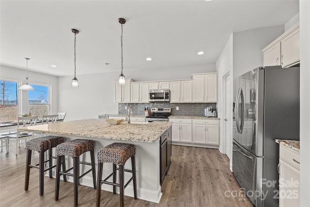 kitchen with white cabinetry, tasteful backsplash, appliances with stainless steel finishes, and wood finished floors