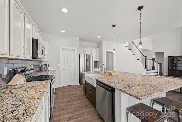 kitchen featuring dark wood-style floors, a breakfast bar, backsplash, appliances with stainless steel finishes, and a sink