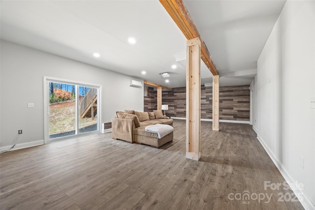 unfurnished living room with an accent wall, wood walls, wood finished floors, and recessed lighting