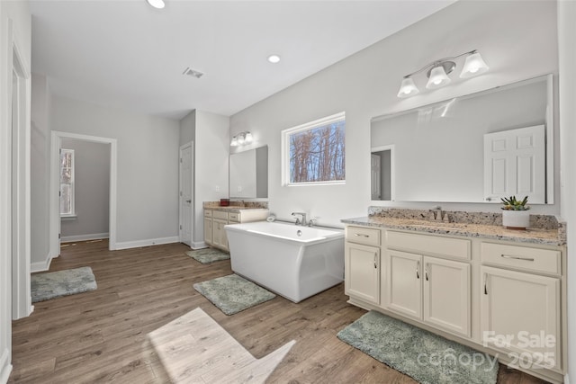 13701 Petworth Ct, Charlotte, NC 28278 - bathroom with wood finished floors, two vanities, a freestanding bath, baseboards, and recessed lighting