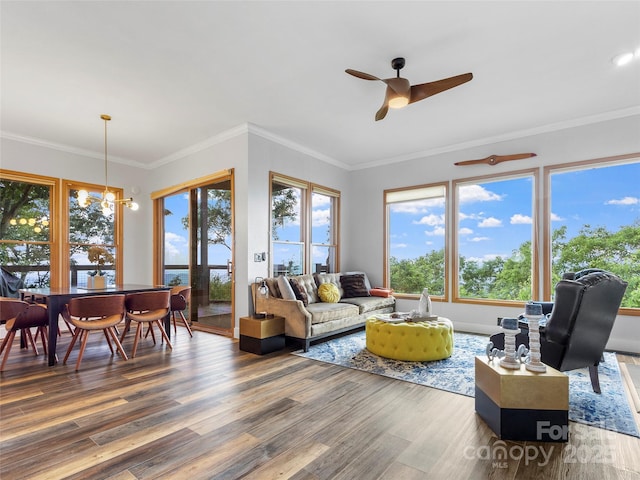 living room featuring ceiling fan with notable chandelier, ornamental molding, and wood finished floors