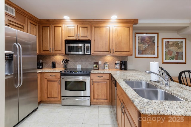 kitchen featuring stainless steel appliances, backsplash, a sink, and brown cabinets