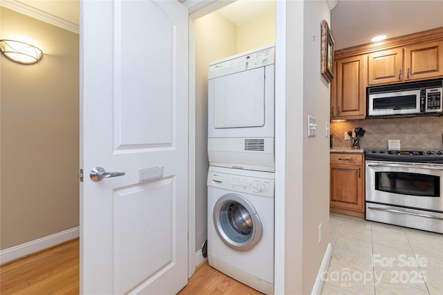 washroom with stacked washer and dryer, baseboards, laundry area, and light tile patterned flooring