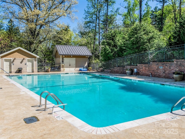 pool featuring an outbuilding, a patio area, and fence