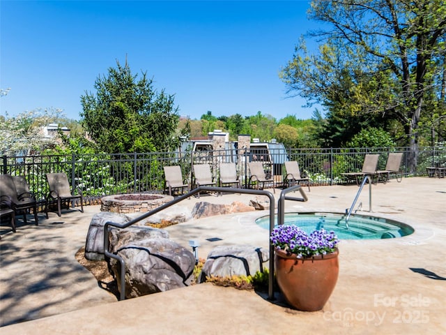 view of swimming pool featuring a community hot tub, a patio area, and fence