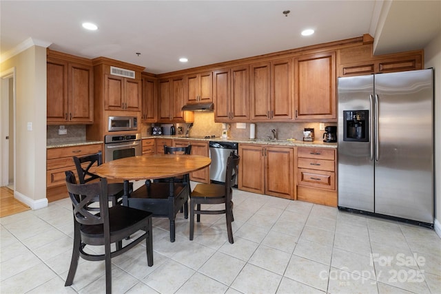 kitchen featuring appliances with stainless steel finishes, brown cabinetry, visible vents, and a sink