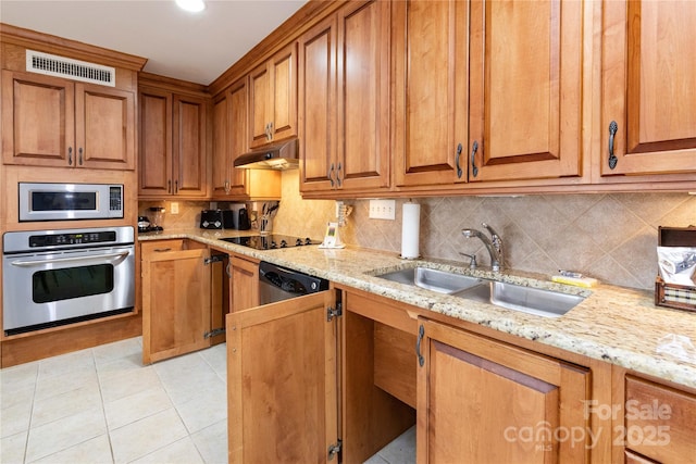 kitchen with under cabinet range hood, stainless steel appliances, a sink, visible vents, and backsplash