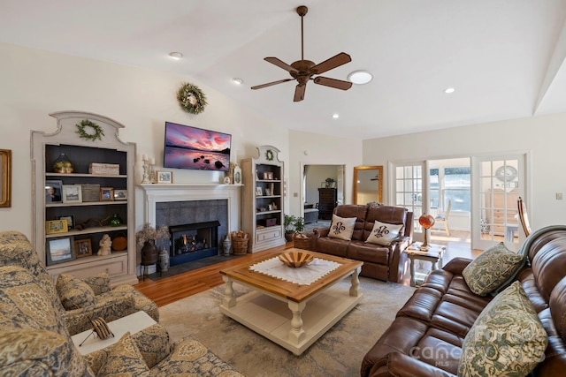 living room featuring wood finished floors, a ceiling fan, lofted ceiling, recessed lighting, and a tiled fireplace