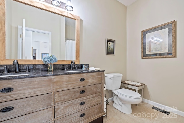 full bathroom featuring a sink, baseboards, toilet, and double vanity