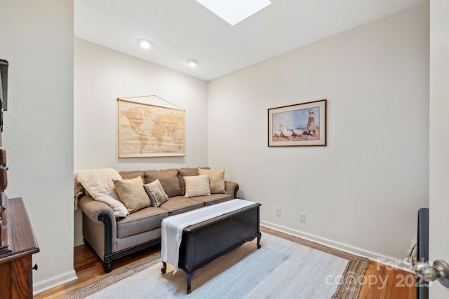 living room featuring a skylight, wood finished floors, and baseboards