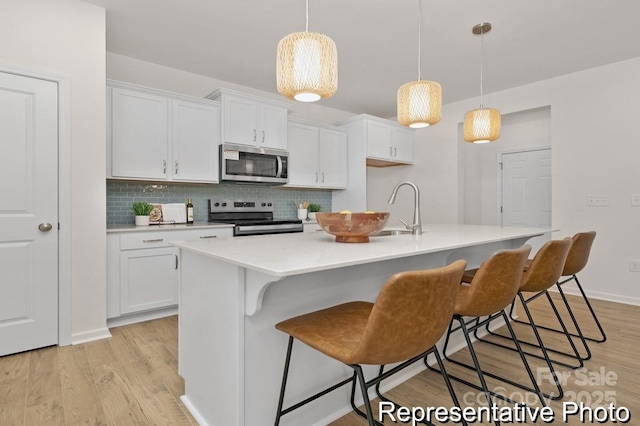 kitchen featuring white cabinetry, appliances with stainless steel finishes, light countertops, and a sink