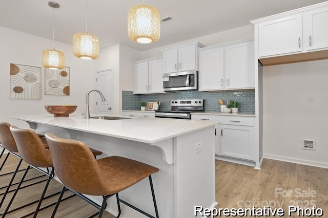 kitchen featuring appliances with stainless steel finishes, pendant lighting, and white cabinets