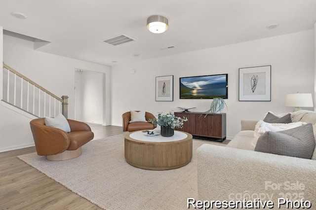 living area featuring stairs, light wood finished floors, visible vents, and baseboards