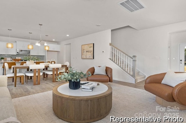 living room with light wood finished floors, stairs, visible vents, and recessed lighting