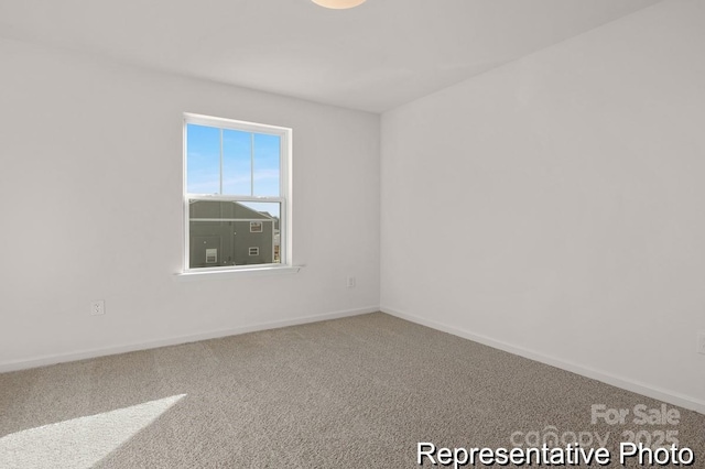 spare room featuring carpet and baseboards