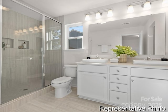 bathroom featuring toilet, a shower stall, and a sink