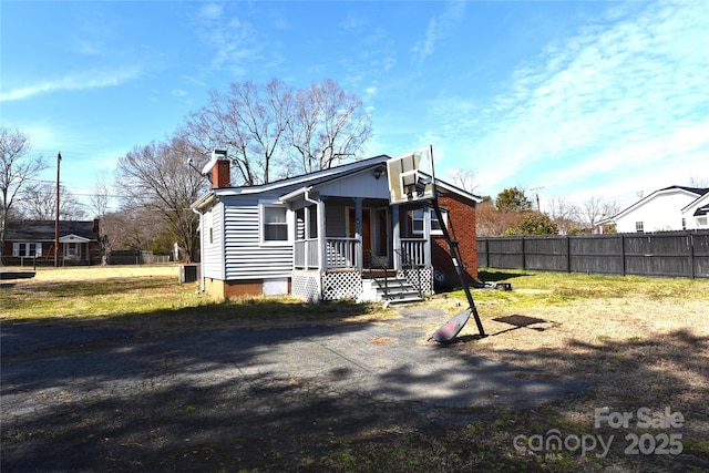 view of front facade with a front yard, fence, and a chimney