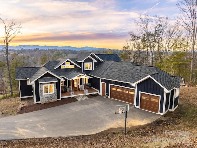 view of front of property with aphalt driveway, an attached garage, a mountain view, covered porch, and board and batten siding