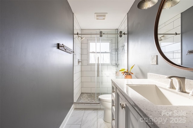 full bathroom featuring toilet, marble finish floor, a stall shower, and vanity