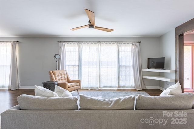 living room featuring dark wood-style floors, ceiling fan, and baseboards