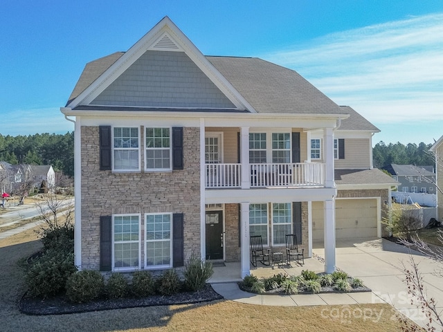 view of front of property featuring stone siding, driveway, an attached garage, and a balcony