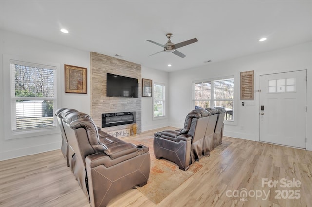 living area with baseboards, light wood-type flooring, a tile fireplace, and recessed lighting