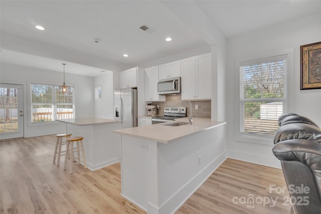 kitchen featuring visible vents, light countertops, backsplash, appliances with stainless steel finishes, and a sink