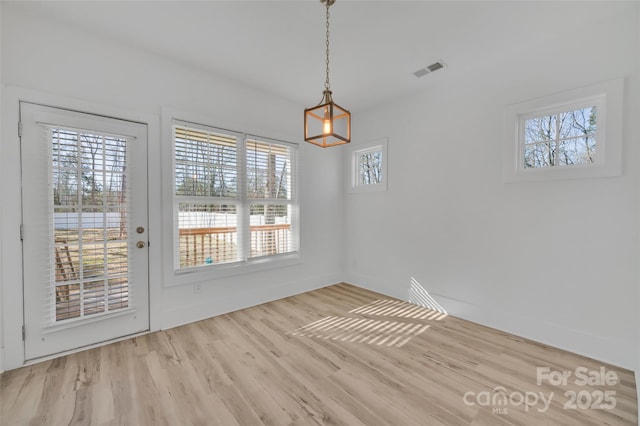 unfurnished dining area featuring baseboards, visible vents, and wood finished floors