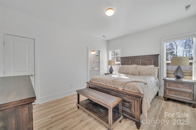 bedroom featuring baseboards, visible vents, light wood finished floors, and ensuite bathroom