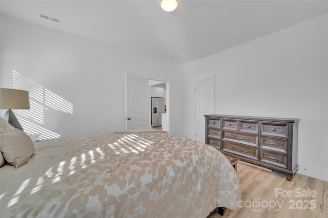 bedroom featuring visible vents, stainless steel refrigerator with ice dispenser, and wood finished floors