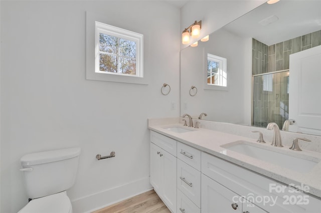 full bathroom with a sink, a tile shower, toilet, and double vanity