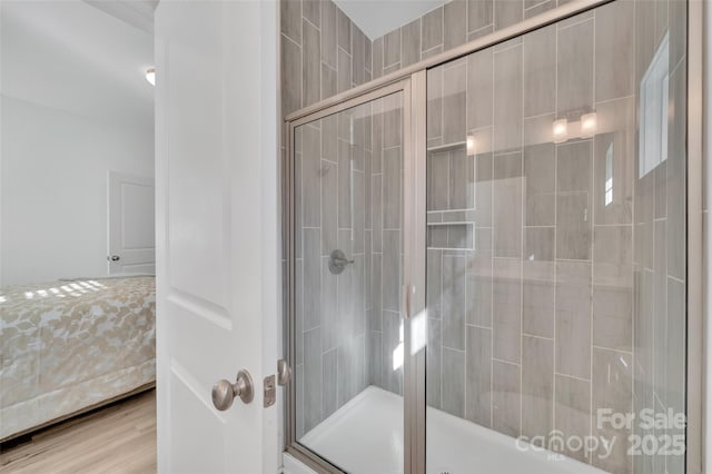 bathroom with wood finished floors, a shower stall, and ensuite bathroom