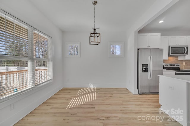 unfurnished dining area with light wood-style flooring, baseboards, and recessed lighting