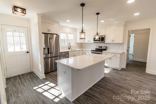 kitchen with dark wood finished floors, stainless steel appliances, decorative backsplash, white cabinets, and a sink