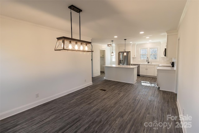 kitchen with crown molding, a kitchen island, stainless steel appliances, and a sink