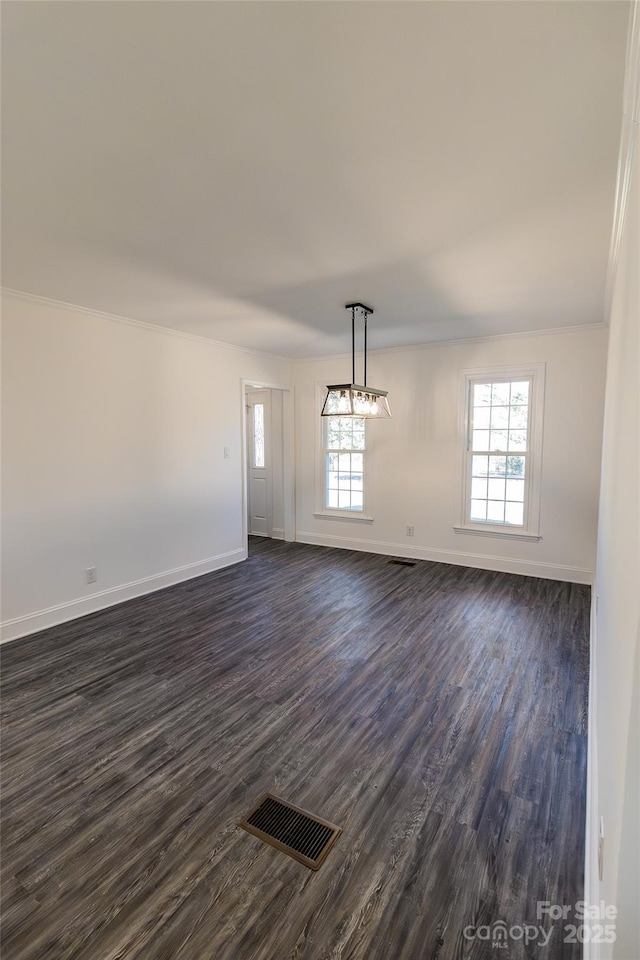 unfurnished dining area featuring baseboards, visible vents, dark wood-type flooring, and ornamental molding