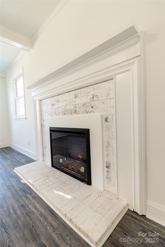 room details with ornamental molding, a glass covered fireplace, baseboards, and wood finished floors