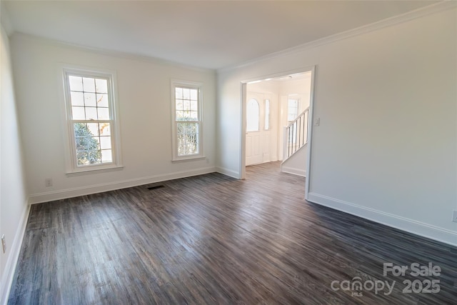 empty room featuring crown molding, dark wood finished floors, stairway, and baseboards