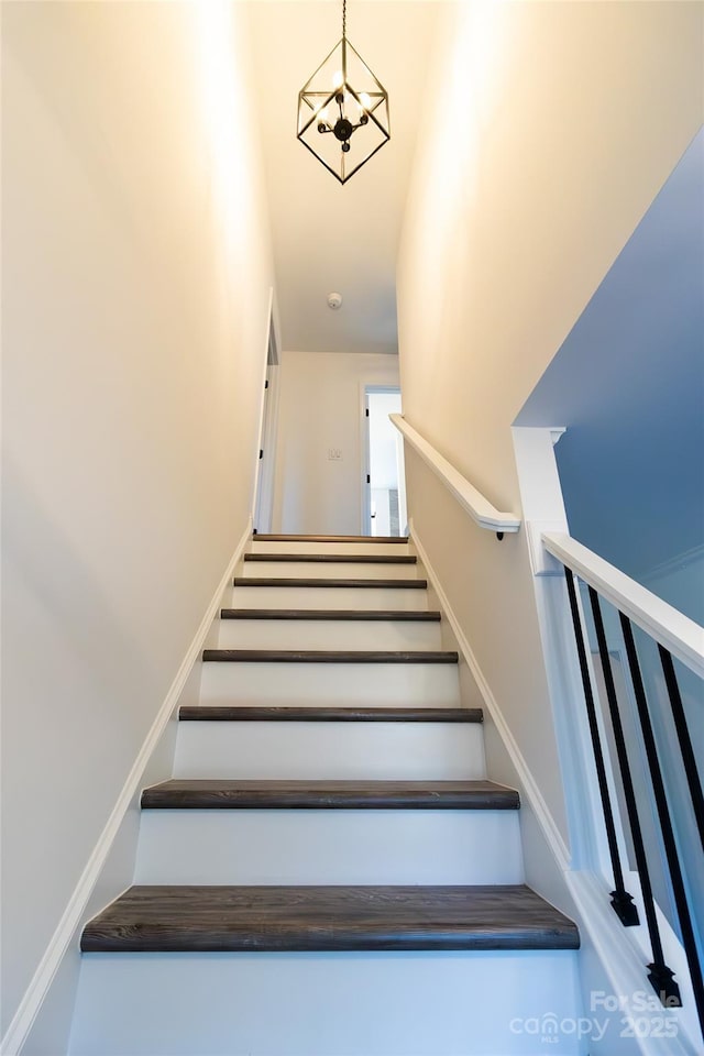 stairs featuring a chandelier and baseboards