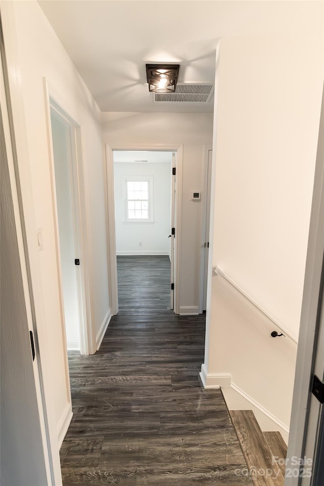 corridor featuring dark wood-style floors, visible vents, and baseboards